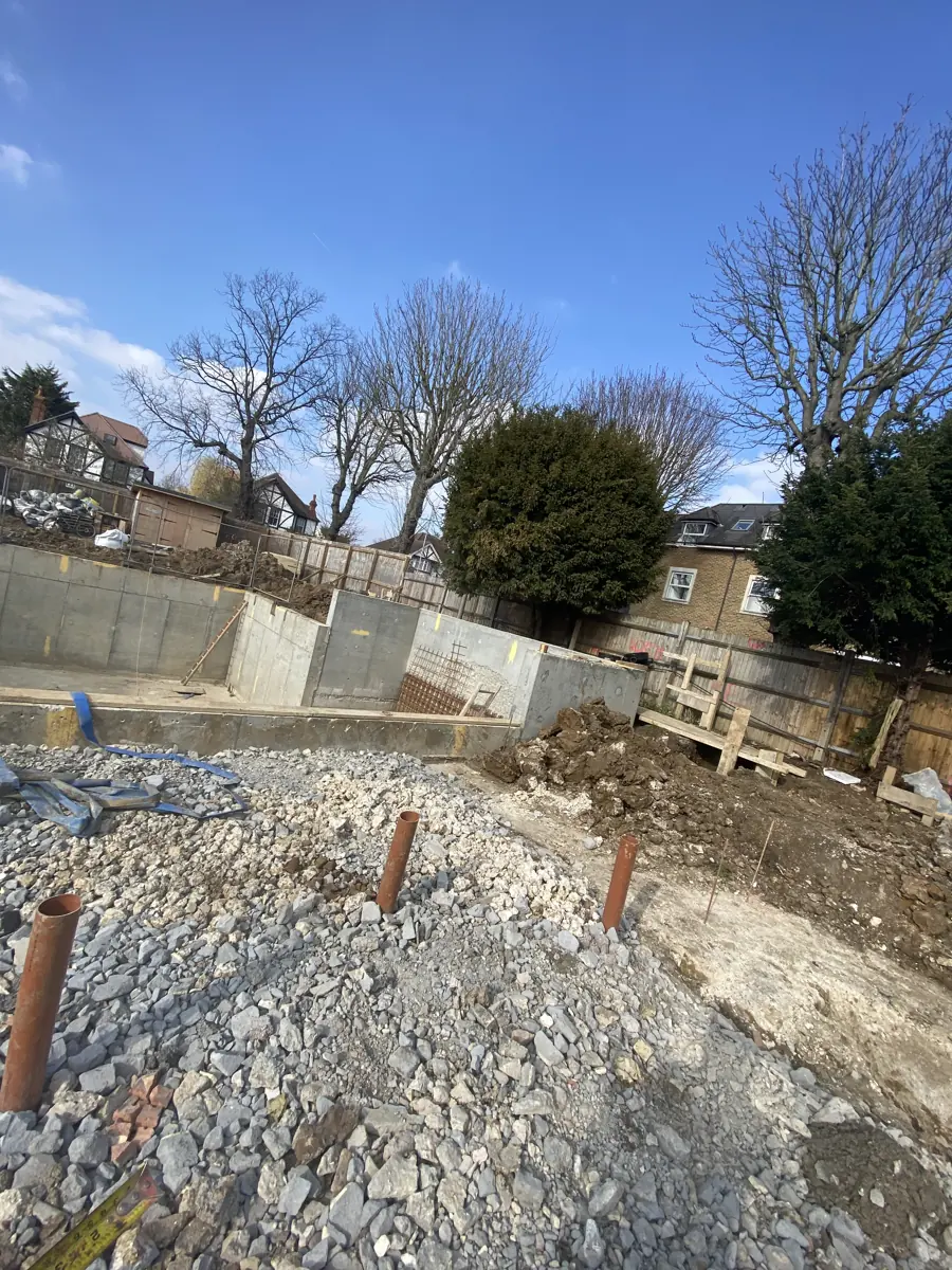 Cast reinforced-concrete basement retaining walls with starter rebar, hardcore and drainage upstands in the foreground
