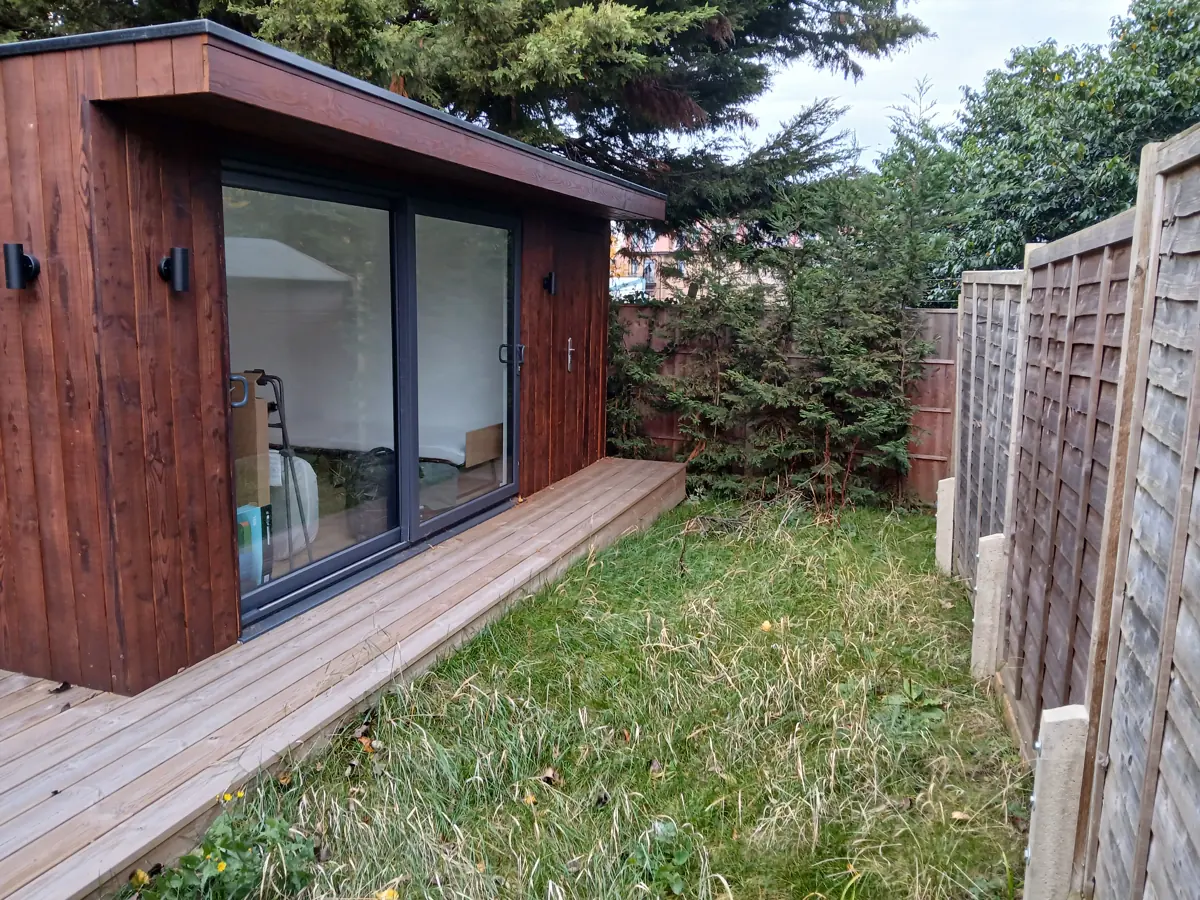 Timber-clad garden building with glazed doors and decking, surveyed for the structural report