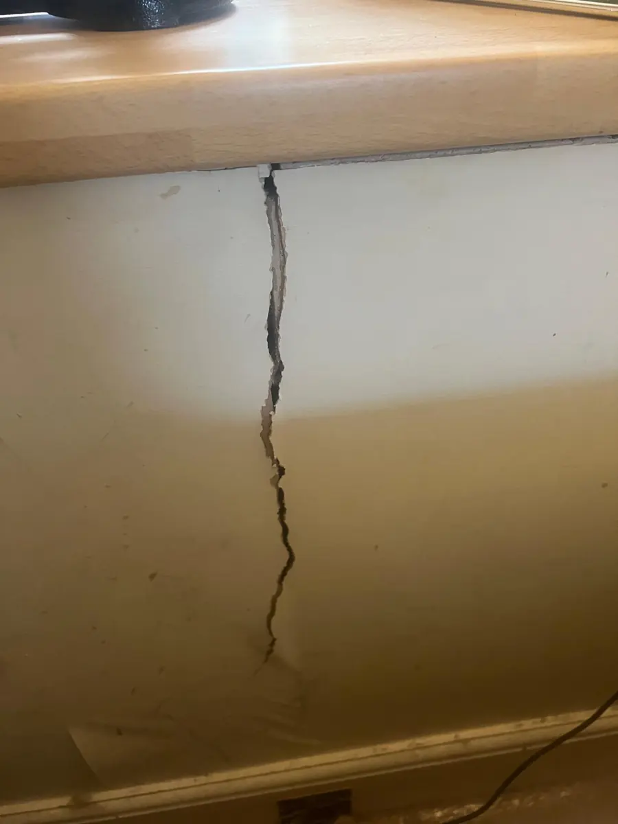 Open vertical crack in plaster below a worktop