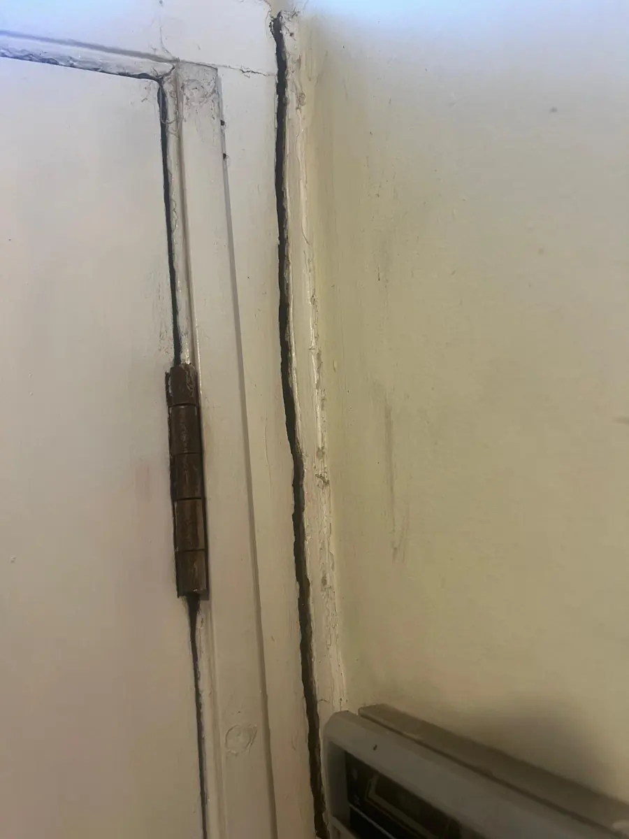Distorted door frame with an open gap between the architrave and the wall