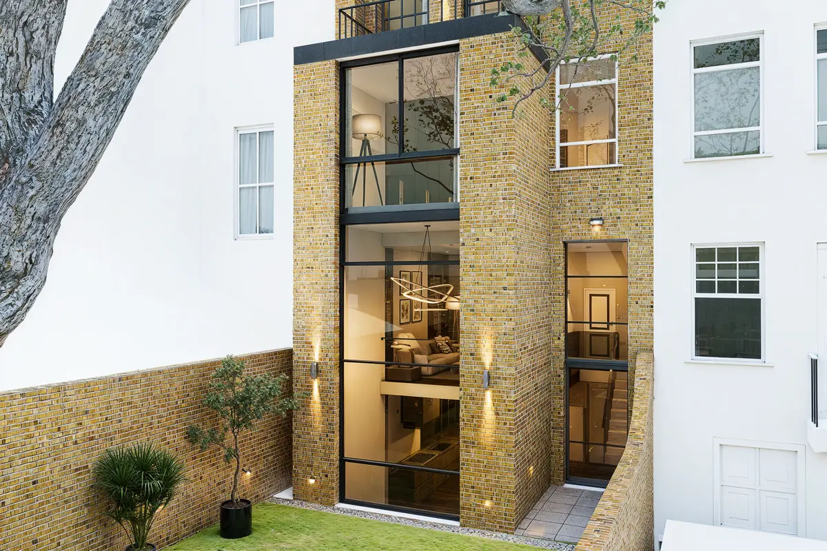 CGI render of the proposed rear: brick rear extension with tall steel-framed glazing showing the floors and new stair inside