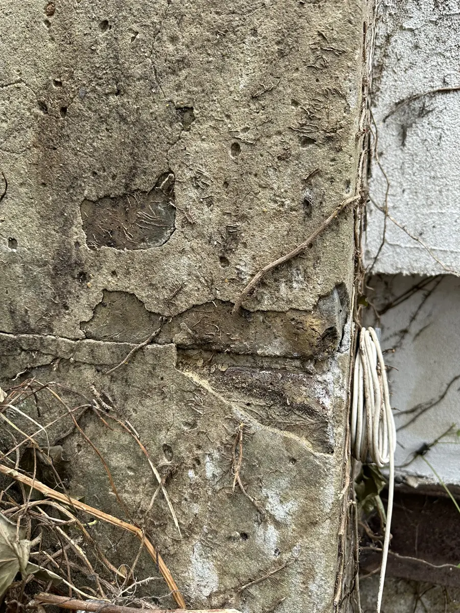 Close-up of spalled render/concrete on the wall showing poor-quality construction