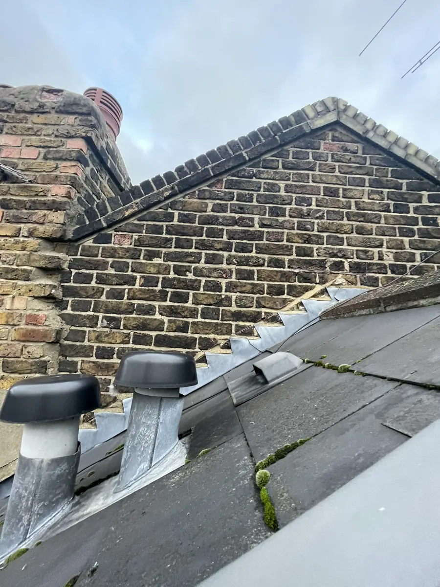 Roof level: brick party-wall gable with stepped lead flashing, slate roof and vent terminals