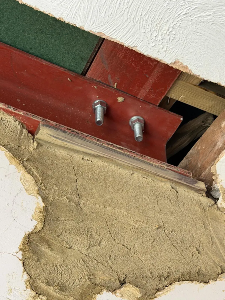 Opened-up ceiling showing new red-oxide steel beam with bolted connection