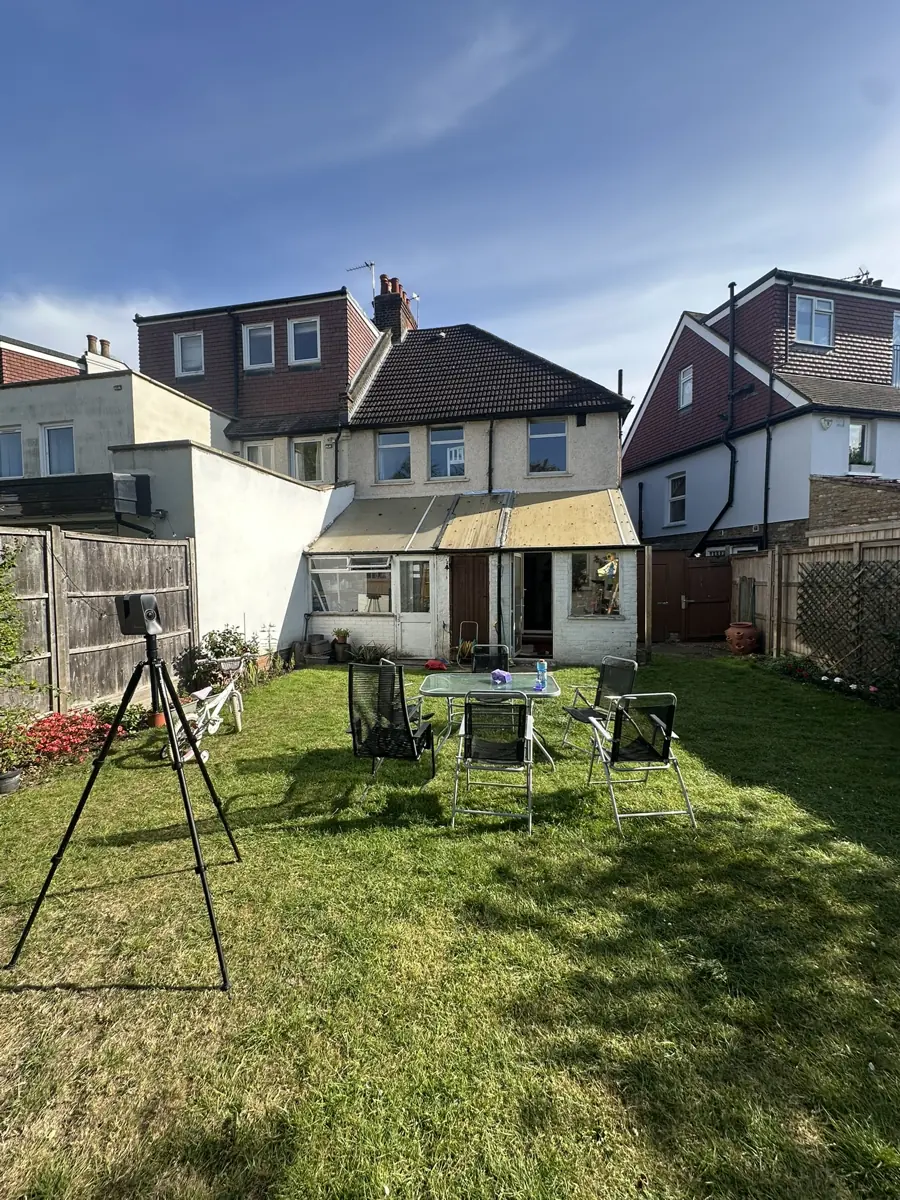 Rear elevation of the existing semi-detached house with the old lean-to that the new rear extension replaces; survey scanner on tripod in garden