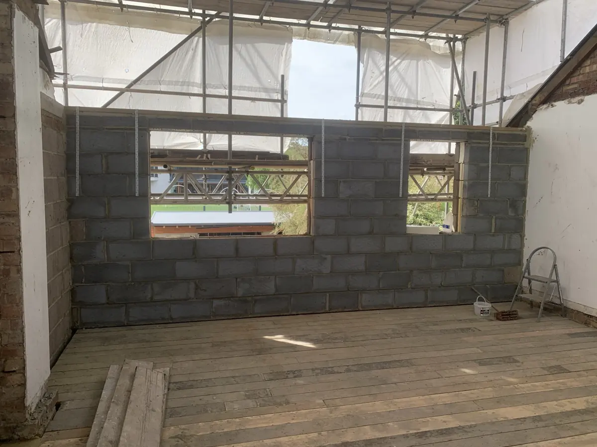 Inside the new dormer: blockwork dormer rear wall with window openings and restraint straps, scaffold behind, new floor boards