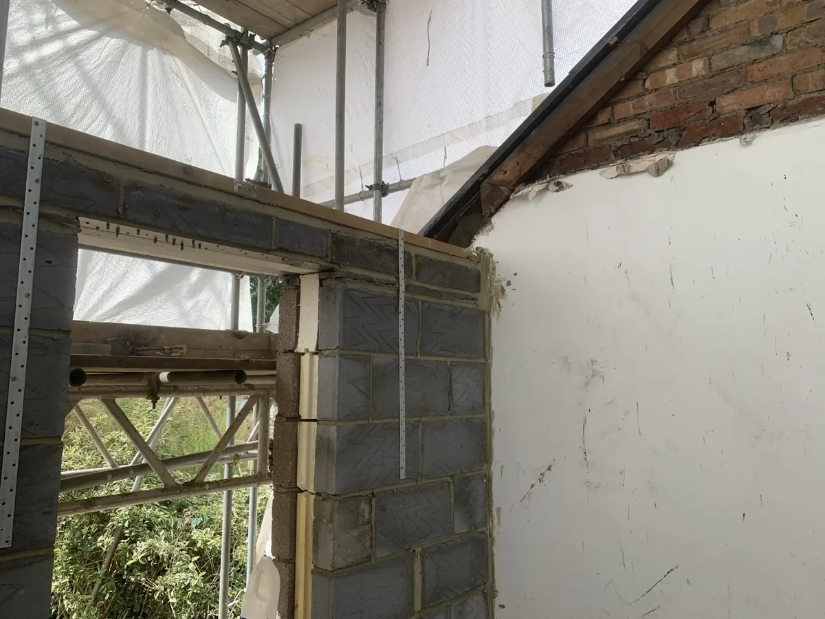 Junction of new dormer side wall and window opening with scaffold, lintel over opening