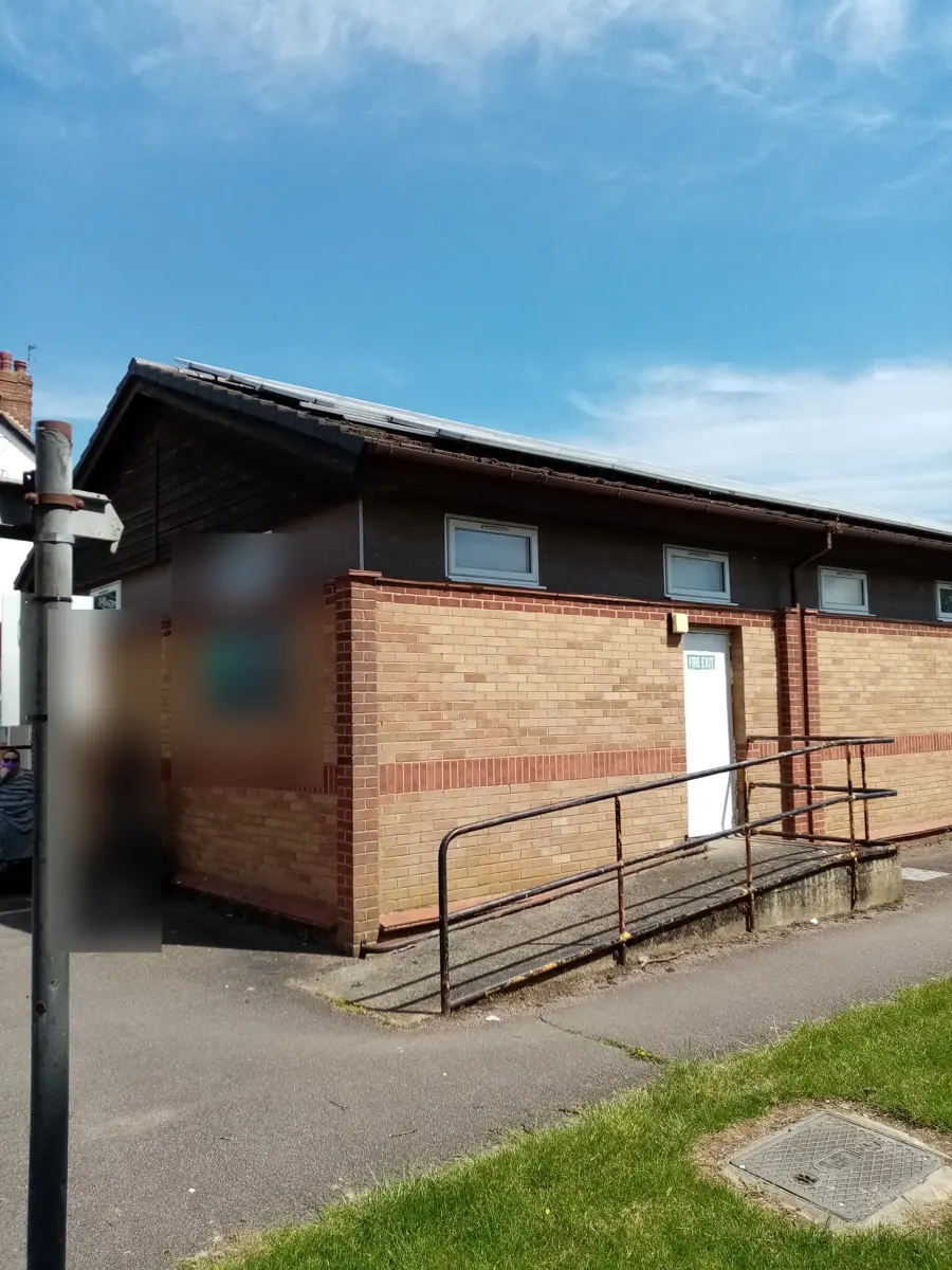 Existing single-storey brick commercial building on the site, with pitched roof and solar panels
