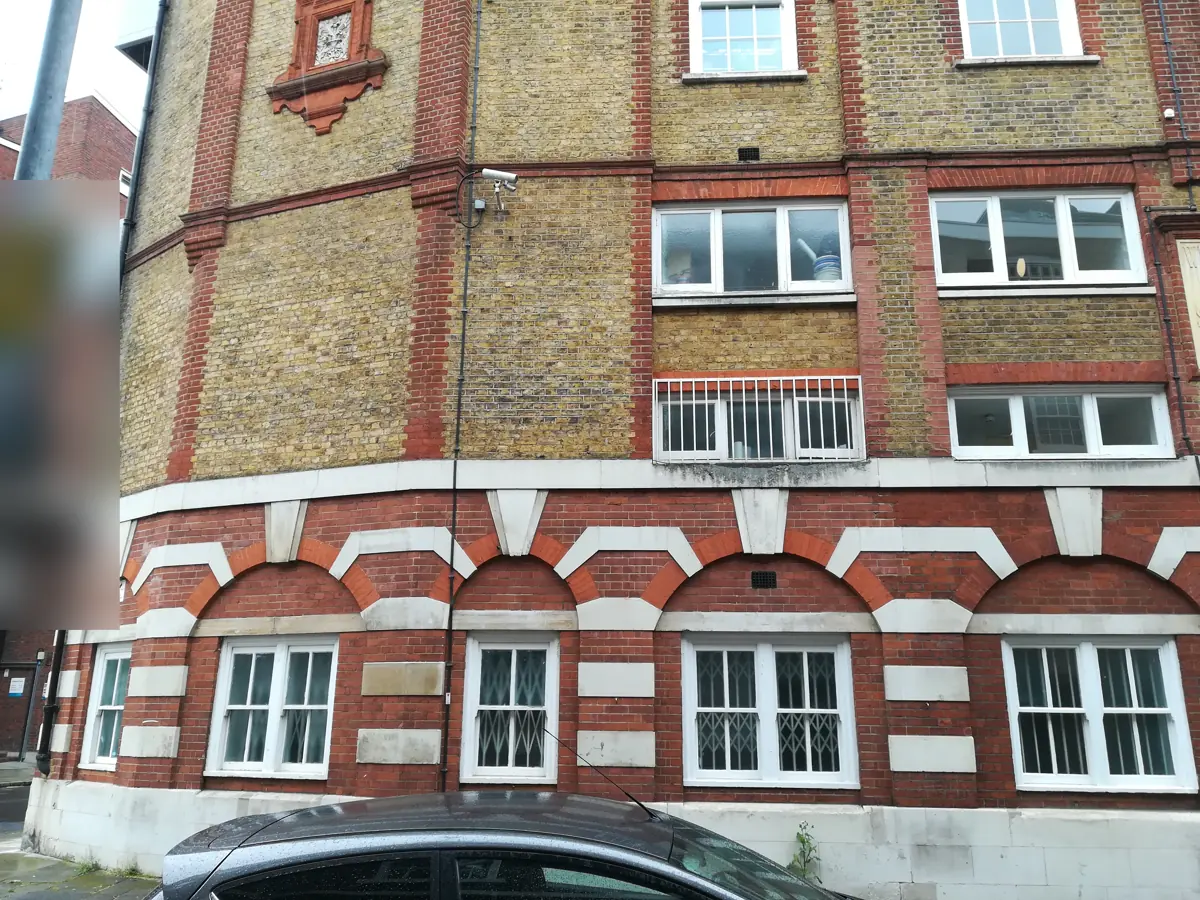Exterior of the Victorian red and yellow brick warehouse building, with arched ground floor windows and stone bands